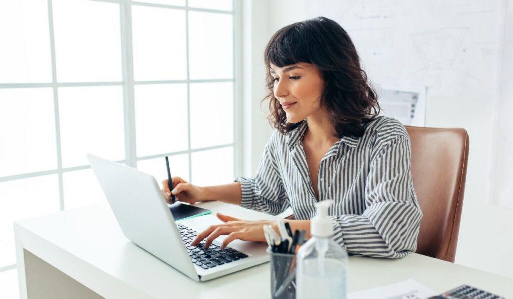 Woman on her laptop researching and choosing a life coach training program.