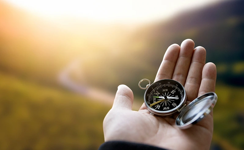 hand holding a compass looking at the horizon