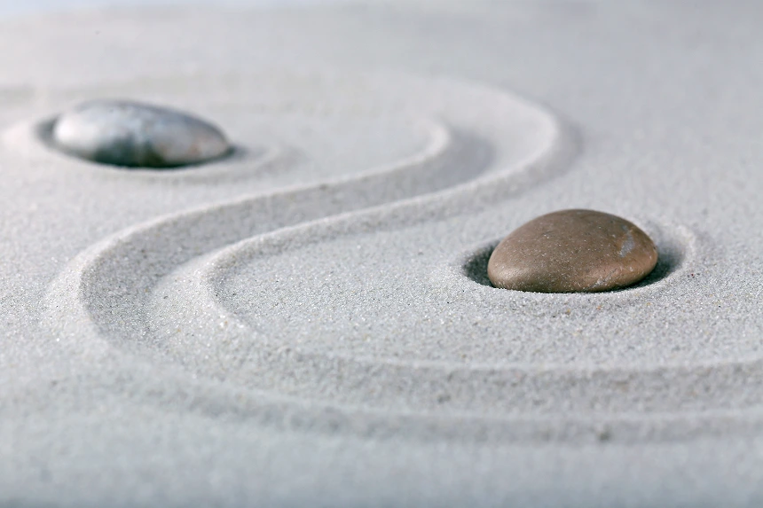 stones forming a yin yang symbol in the sand