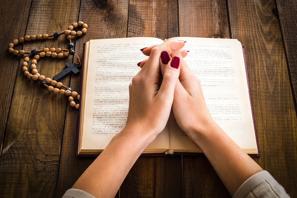 woman doing her prayer routine with a bible and a rosary